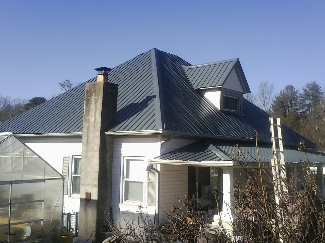 Dark blue standing seam metal roof on a white farmhouse with dormer — Slate & Tile Roof Repair by Roofing Brothers in Gretna