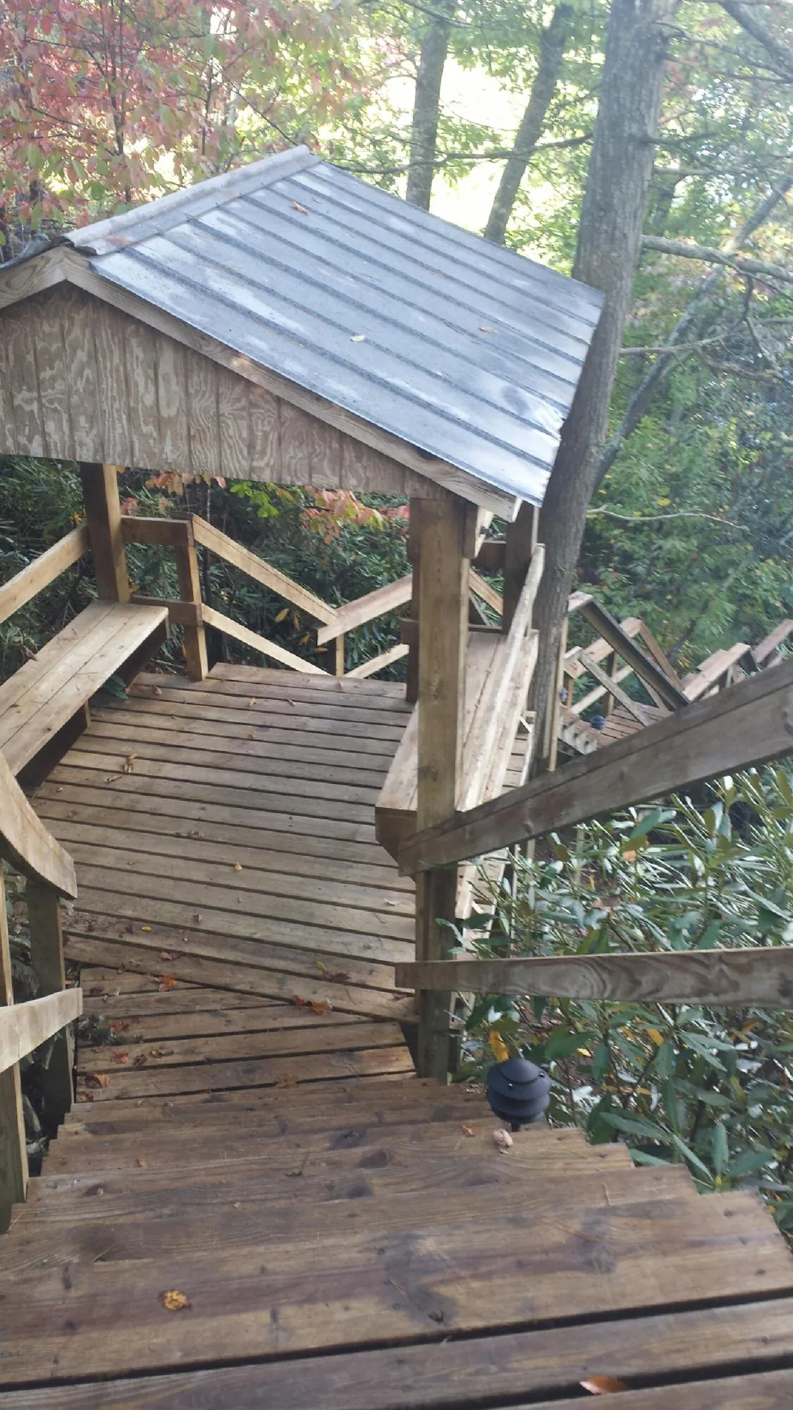 Metal roofed shelter over wooden steps on a wooded walkway — Skylight Repair & Installation work by our crew in Gretna